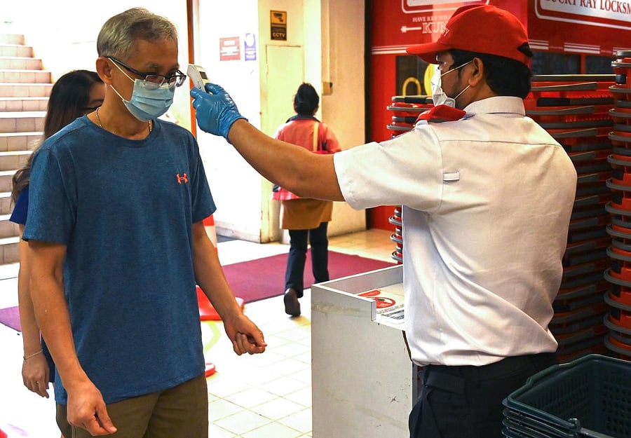 A security guard checks the temperatureas a partial lockdown continues in Malaysia amid fears over the spread of the COVID-19 (AFP Photo)
