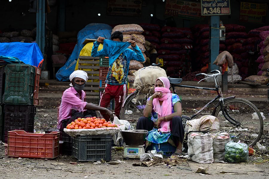 Vegetable vendors with their faces covered wait for customers during a government-imposed nationwide lockdown as a preventive measure against the COVID-19. (Credit: AFP)