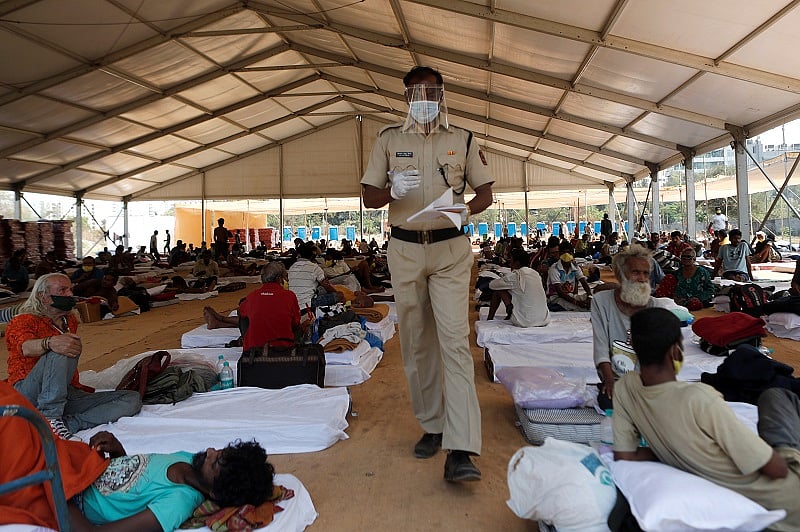 A policeman wearing a protective mask walks inside a shelter set up for migrants during a 21-day nationwide lockdown. (PTI Photo)