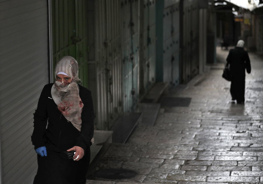 A woman walks in an alley past closed shops due to the COVID-19 coronavirus pandemic in Jerusalem's Old City/ Representative photo. (Credit: AFP)