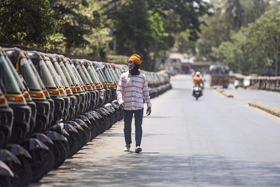 A pedestrian wearing a mask walks past parked auto rickshaw during the nationwide lockdown, in wake of the coronavirus pandemic, at Kandivali in Mumbai, Friday, April 10, 2020. (PTI Photo)