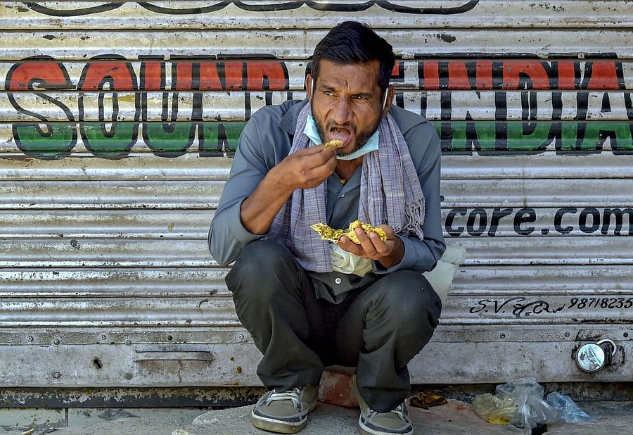 A homeless man consumes food distributed by volunteers near Gurudwara Sis Ganj Sahib, during the nationwide lockdown to curb the spread of coronavirus, at Chandni Chowk in Old Delhi, Sunday, April 12, 2020. Credit: PTI Photo