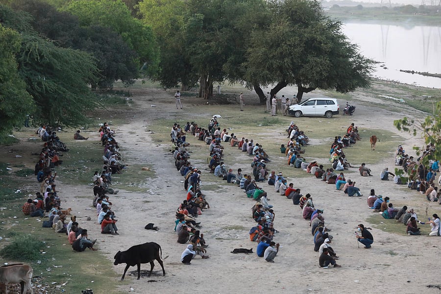 Daily wage workers and homeless people wait on the banks of Yamuna river to be transferred to a shelter (Reuters Photo)