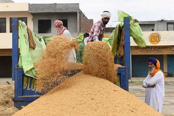 Labourers unload rice from a trolley during a government-imposed nationwide lockdown as a preventive measure against the COVID-19 coronavirus at a grain market in Amritsar. (Credit: AFP Photo)