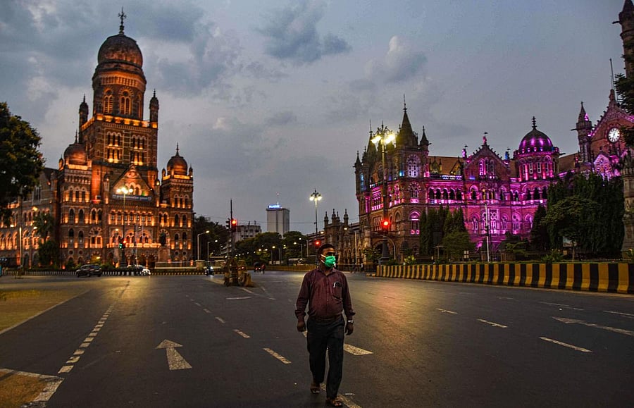 A man walks on a deserted street in the backdrop of illuminated BMC headquarters on World Heritage Day in Mumbai on Saturday. PTI