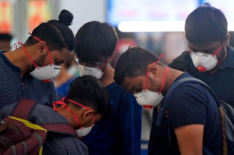 Passengers wearing facemasks amid concerns over the spread of the COVID-19 novel coronavirus, stand in a queue at a counter inside the airport in Goa. (AFP Photo)