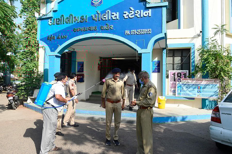 Gujarat police personnel (C) reacts as a worker from the non-governmental organization Shahin Foundation, sprays disinfectant on him, during a government-imposed nationwide lockdown as a preventive measure against the COVID-19 coronavirus, in Ahmedabad. (Credit: AFP Photo)
