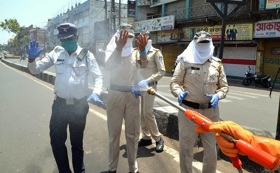 A worker sprays disinfectant on security personnel (PTI Photo)