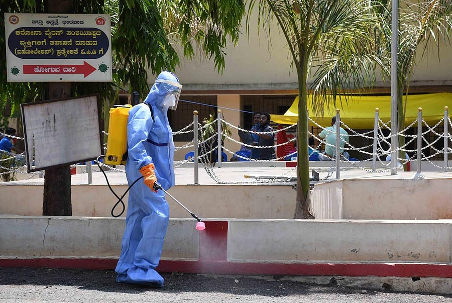 A civic worker sprays disinfectant on the premises of district hospital in Dharwad on Thursday. DH Photo
