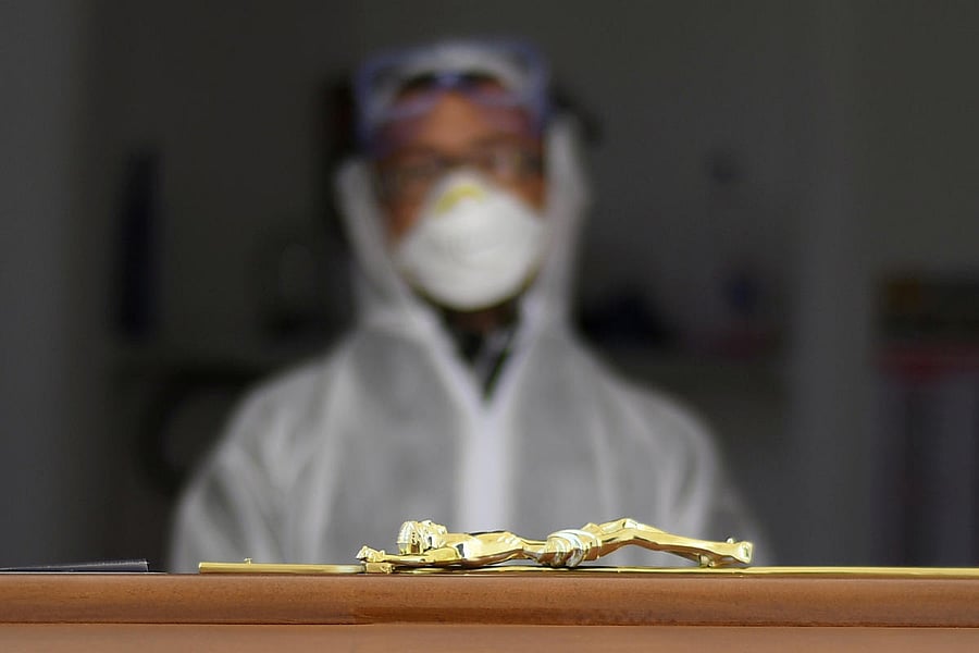 A funeral service worker looks at coffins of two victims of coronavirus disease (COVID-19) during a burial ceremony in the southern town of Cisternino, Italy March 30, 2020. Credit: Reuters File Photo