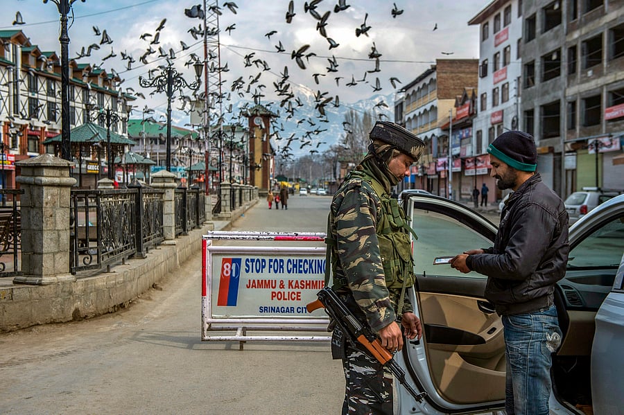 A security personnel checks the identity card of a commuter. (PTI Photo)