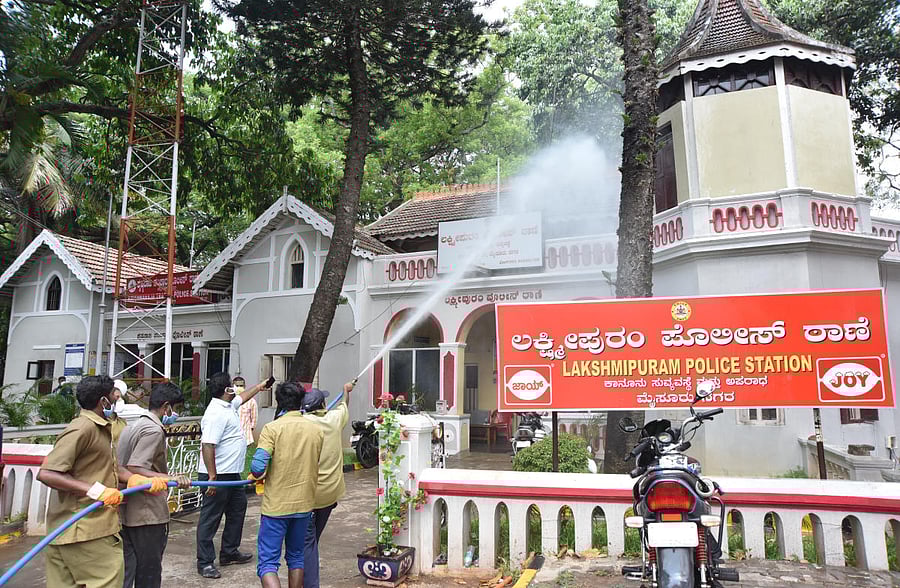 Mysuru City Corporation personnel spray disinfectant on the building of Lakshmipuram Police Station, on Saturday. DH PHOTO