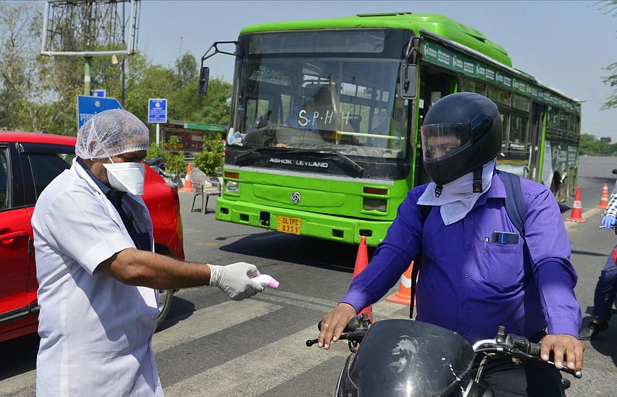 A medic uses a thermal screening device on a commuter entering the sealed Delhi-Noida border (PTI Photo)
