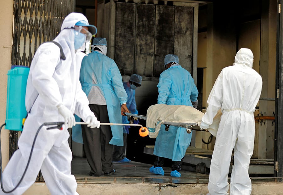 Municipal workers in protective gear carry the body who died due to coronavirus disease (Reuters Photo)