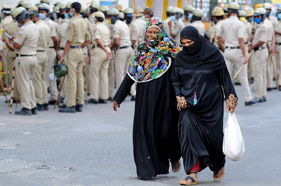 Women walk in Padarayanapura on Tuesday amid a large security presence. DH PHOTO/PUSHKAR V