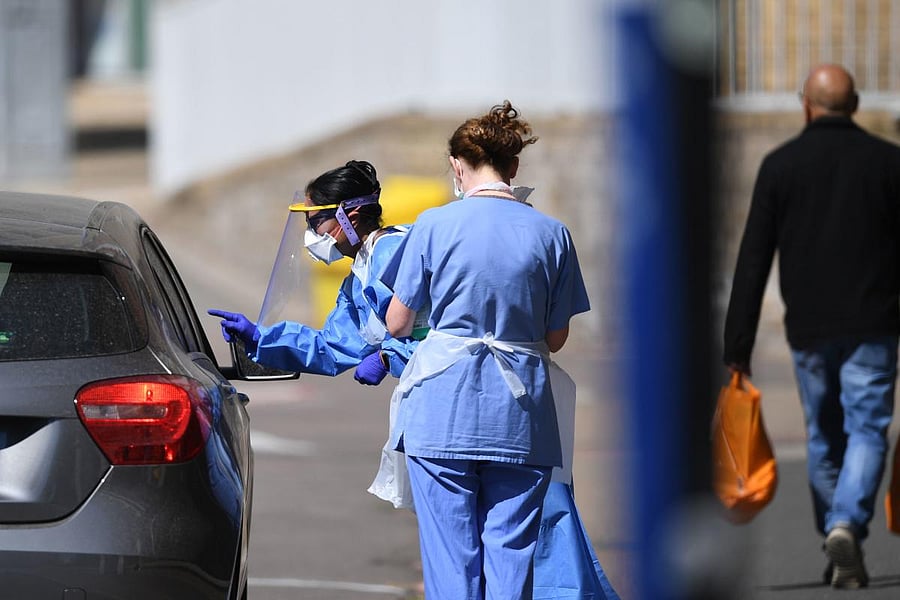 A medical worker explains to an essential worker about a testing kit for the novel coronavirus COVID-19 in LOndon (AFP Photo)