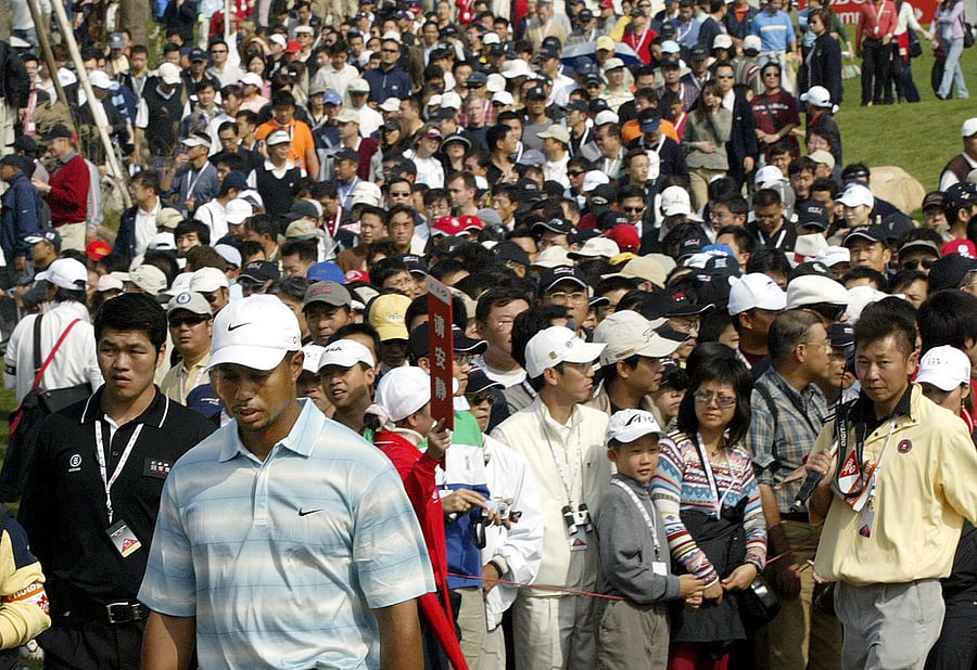 This file photo taken on November 12, 2005 shows US golfer Tiger Woods (front L, in white hat) being followed by a large crowd of Chinese spectators as he walks from the tee-off area during the HSBC Champions golf tournament in Shanghai. (Credit: AFP)