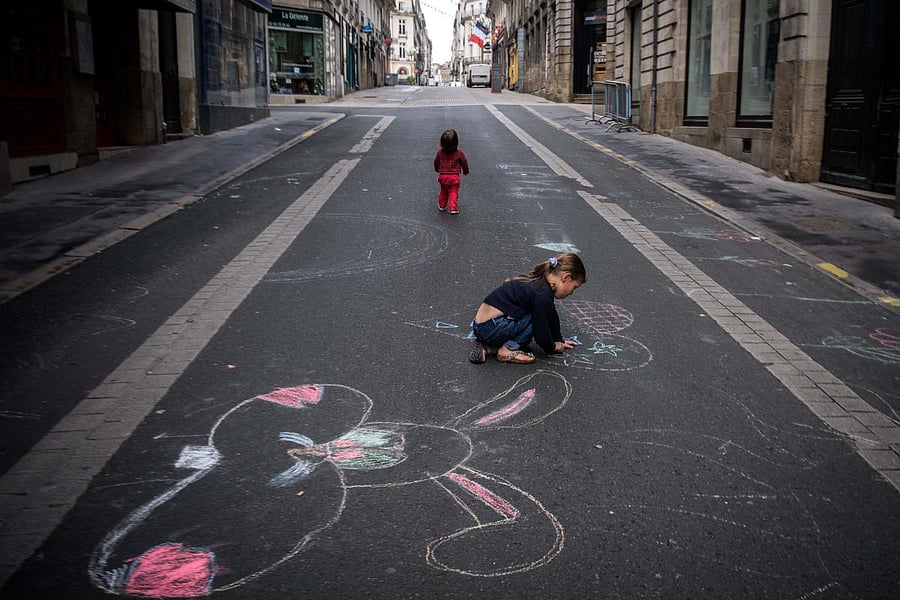 A child draws with chalk on a road in Nantes, on April 27, 2020, as the country is under lockdown to stop the spread of the COVID-19 pandemic caused by the novel coronavirus. Credit: AFP Photo