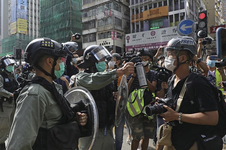 A riot police points the pepper spray to journalists as pro-democracy activists gather outside a shopping mall during the Labor Day in Hong Kong (AP Photo)