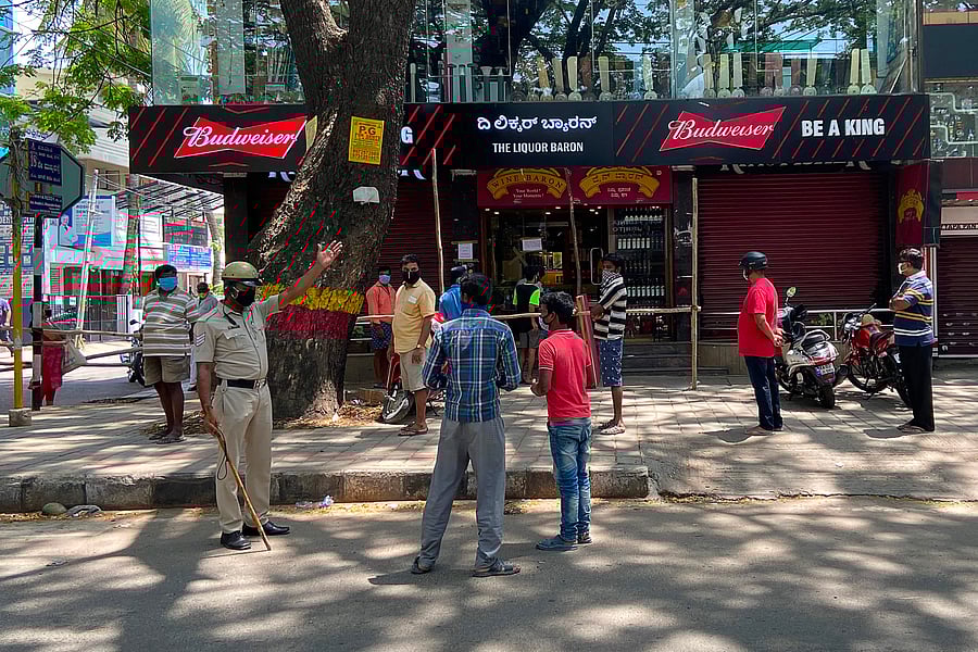 A police personnel (L) gestures as people queue at a liquor store after the government eased a nationwide lockdown imposed as a preventive measure against the COVID-19 coronavirus. (AFP Photo)