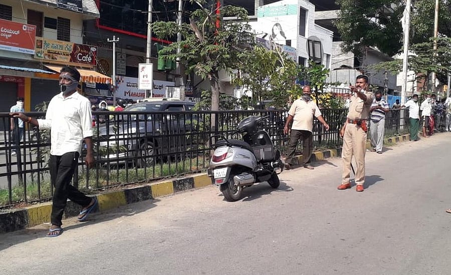 Police control the situation through mild caning on 100 Foot Road in Mandya. DH PHOTO