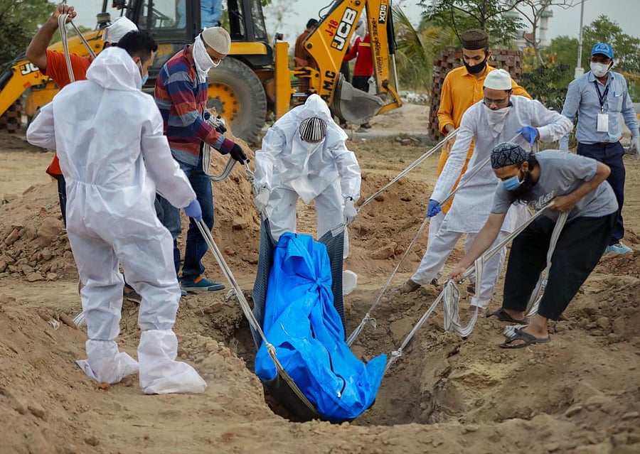  Medics and family members perform burial of a person who died of COVID-19, during the nationwide lockdown (PTI Photo)