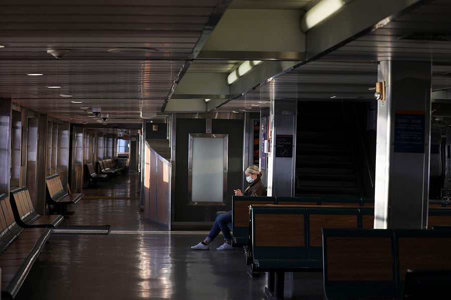 A commuter on the Staten Island Ferry wears a protective face mask and sits alone during the outbreak of the coronavirus disease (COVID-19) in Manhattan. (Credit: Reuters)