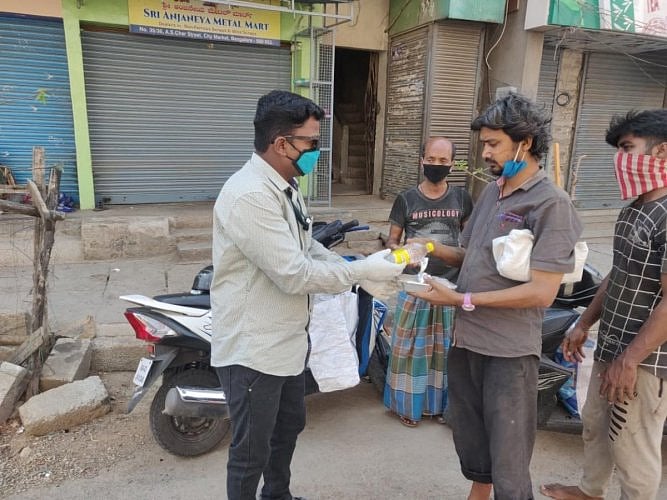 Deepak R distributing food packets to people living on daily wages.