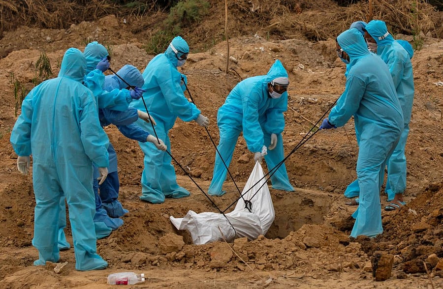 A health worker and relatives lower the body of a man who died from the coronavirus disease (COVID-19), for burial at a graveyard in New Delhi, India, May 6, 2020. REUTERS/Danish Siddiqui TPX IMAGES OF THE DAY