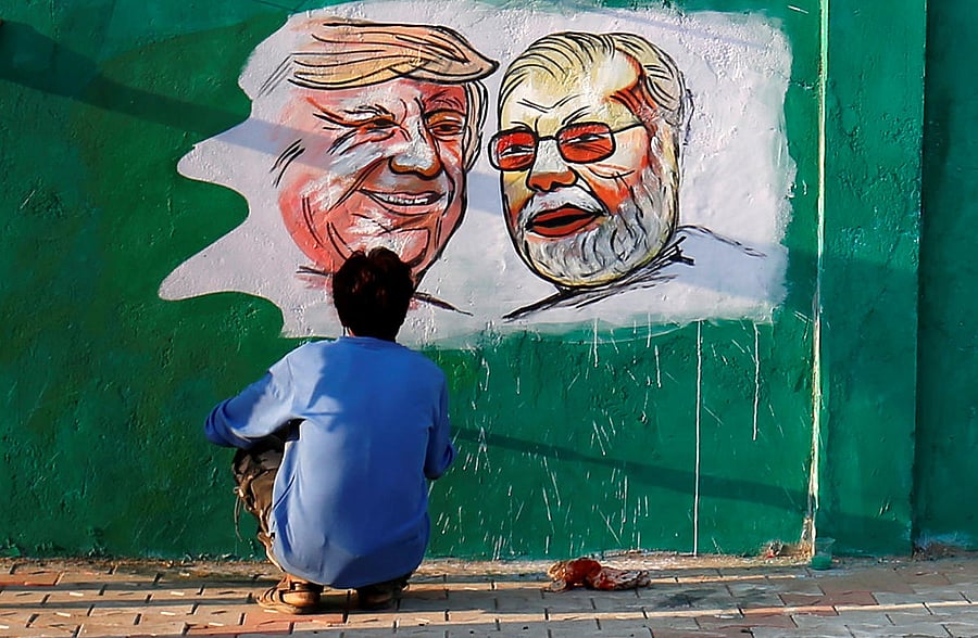 A man applies finishing touches to paintings of U.S. President Donald Trump and India's Prime Minister Narendra Modi on a wall as part of a beautification along a route that Trump and Modi will be taking during Trump's upcoming visit, in Ahmedabad, India, February 17, 2020. (Reuters Photo)