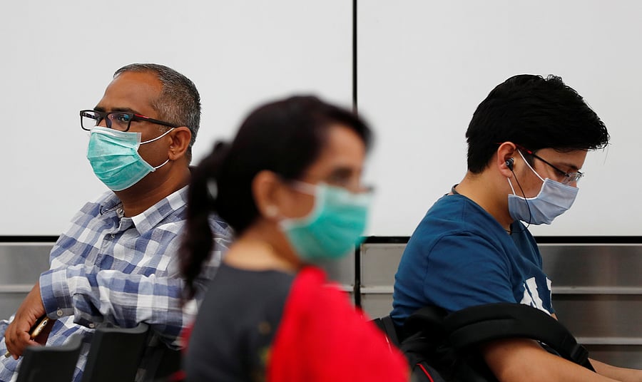 Passengers wearing protective masks sit at an airport terminal following an outbreak of the coronavirus disease (COVID-19), in New Delhi, India. (Reuters Photo)