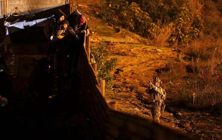 A US Custom and Border Protection (CBP) agent points his weapon at migrants as they prepare to cross the border fence illegally from Mexico into the US, in Tijuana, Mexico, January 1, 2019. (REUTERS)