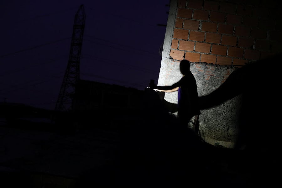 A man uses light from a cellphone at a neighborhood during a blackout in Caracas. Reuters