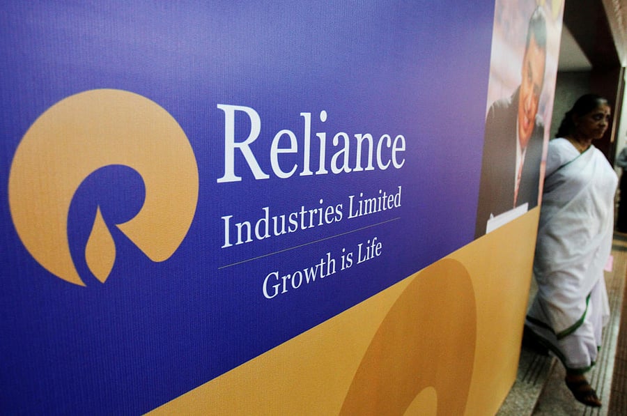 A woman walks past a poster of Reliance Industries installed outside the venue of the company's annual general meeting in Mumbai June 7, 2012. (Reuters Photo)