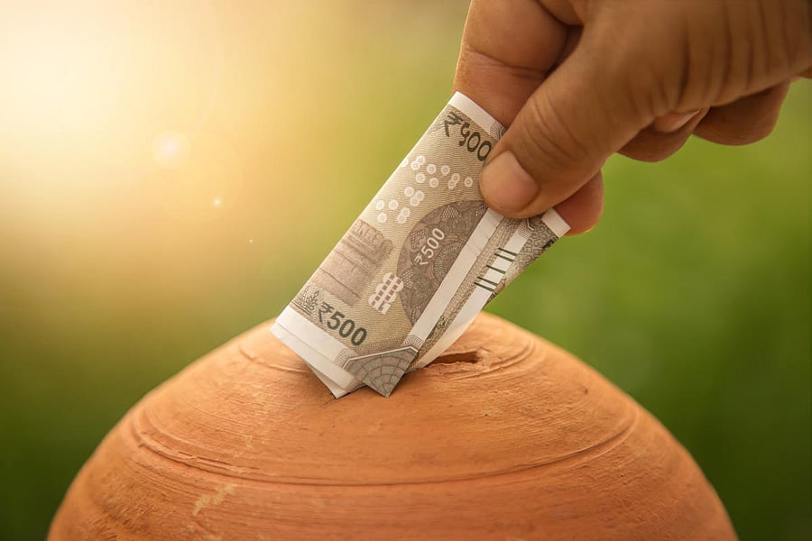 Hand putting money into piggy bank (Getty Image)