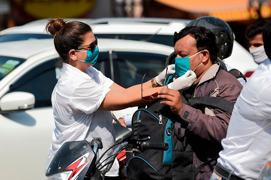 A volunteer of the Humf NGO adjusts a free facemask to a motorist during a facemaks donation campaing amid concerns over the spead of the COVID-19 coronavirus. (AFP Photo)