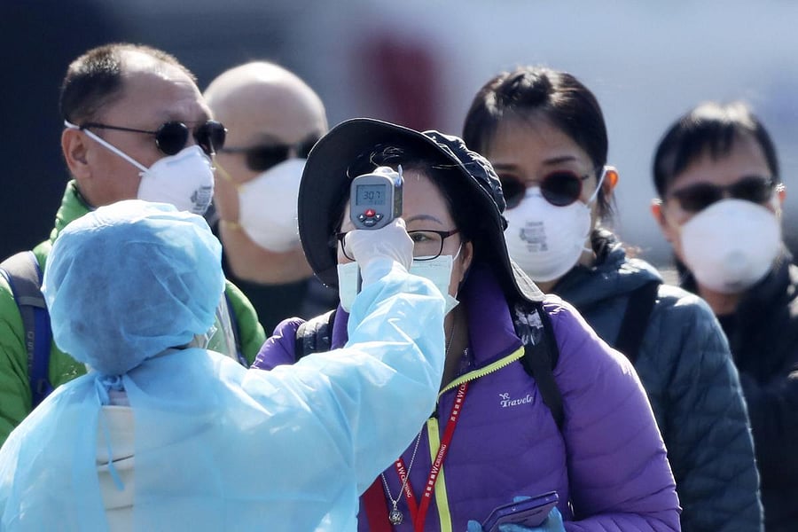 An official in protective suits ensures the temperature of the foreign passengers. (AP Photo)