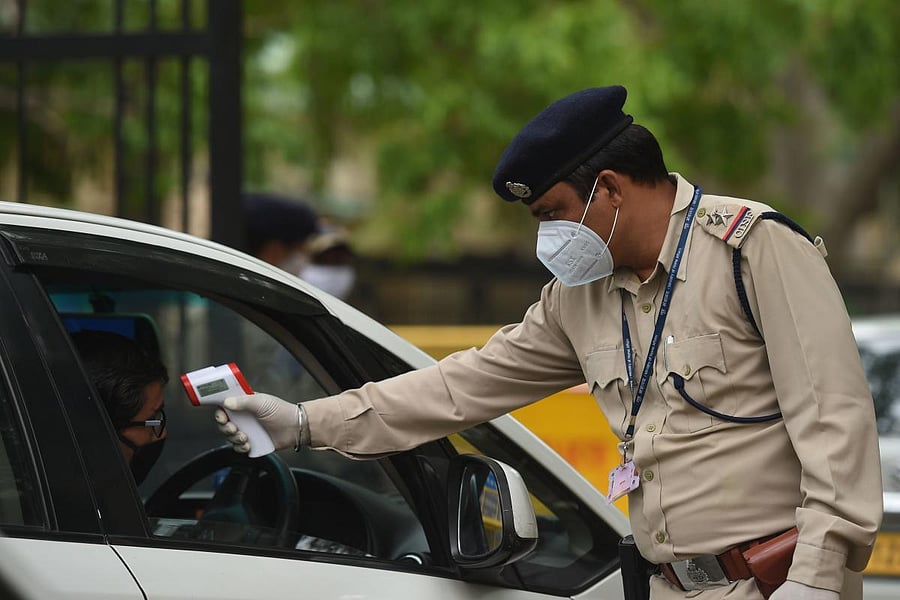 A Central Industrial Security Force (CISF) personnel checks the body temperature of a man at Shastri Bhawan during a government-imposed nationwide lockdown as a preventive measure against the COVID-19 coronavirus, in New Delhi on April 20, 2020. Credit: AFP Photo