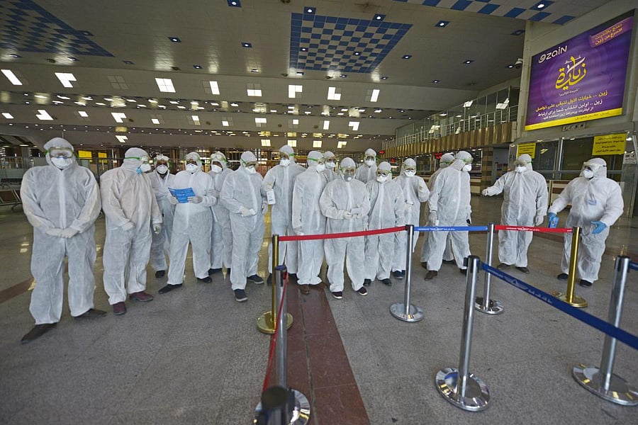Medical staff in protective gear wait for Iraqi passengers returning from Iran at Najaf International Airport on March 5, 2020. - Iraqi health authorities announced the country's first two deaths from the new coronavirus, one in the capital Baghdad and th