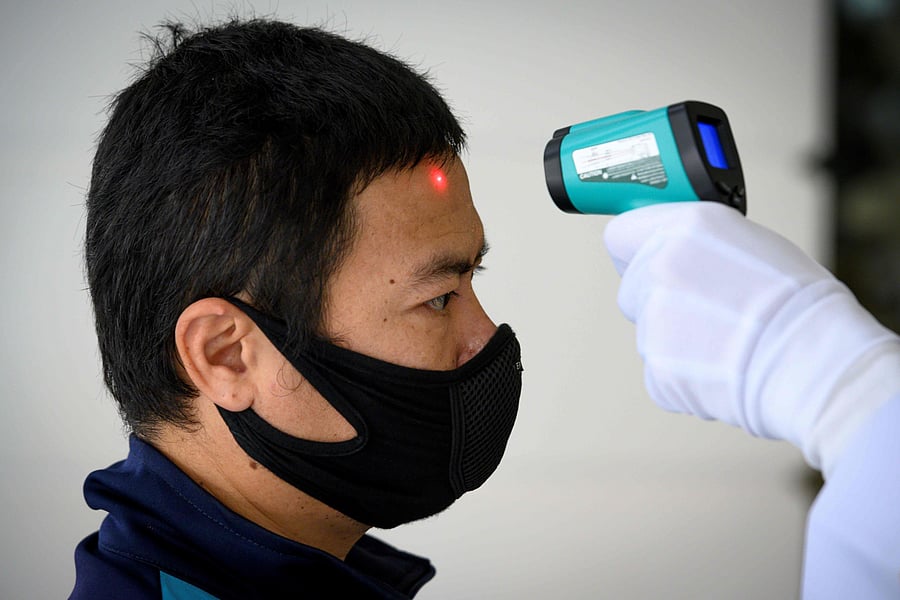 A man, wearing a face mask as a preventive measure against the COVID-19 novel coronavirus, gets his temperature checked before entering a building in Bangkok. (AFP Photo)