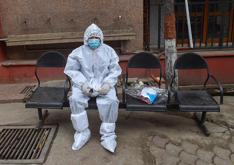 A man wearing protective suits sits after performing last rites of his father, who died of COVID-19. PTI