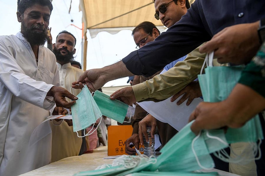 Workers of ruling Pakistan Tehreek-e-Insaf (PTI) political party, distribute facemasks and pamphlets about basic protective measures against the COVID-19 coronavirus to residents along a street in Karachi on March 10, 2020. (AFP Photo)