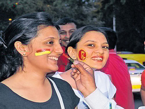 Cricket fans get their favourite team logo painted on their faces near Chinnaswamy Stadium ahead of an IPL match between Royal Challengers Bangalore and Delhi Daredevils on Sunday. dh photo