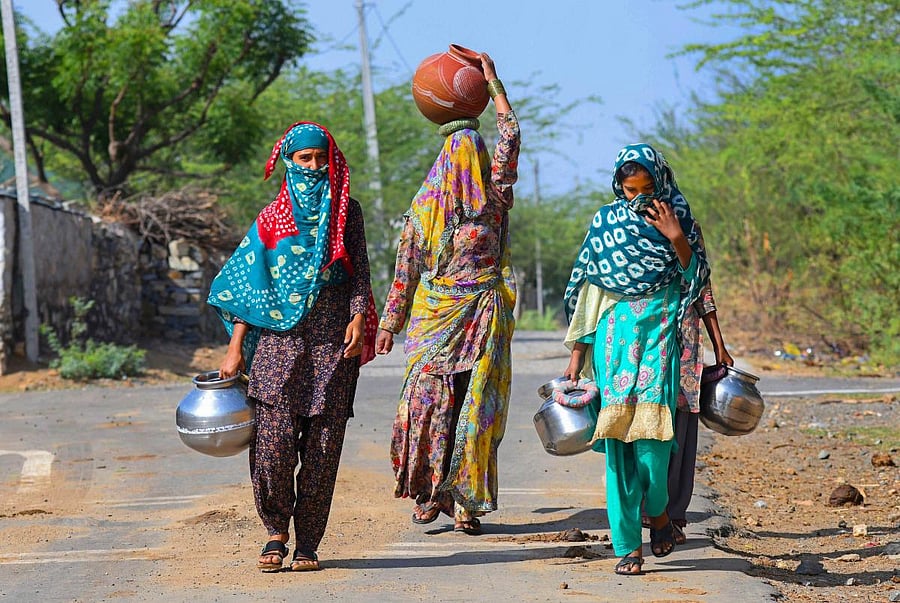  Women carry vessels to collect water from a public tap, during the nationwide lockdown to curb the spread of coronavirus, at Jagmalpura village near in Beawar. Credit: PTI Photo