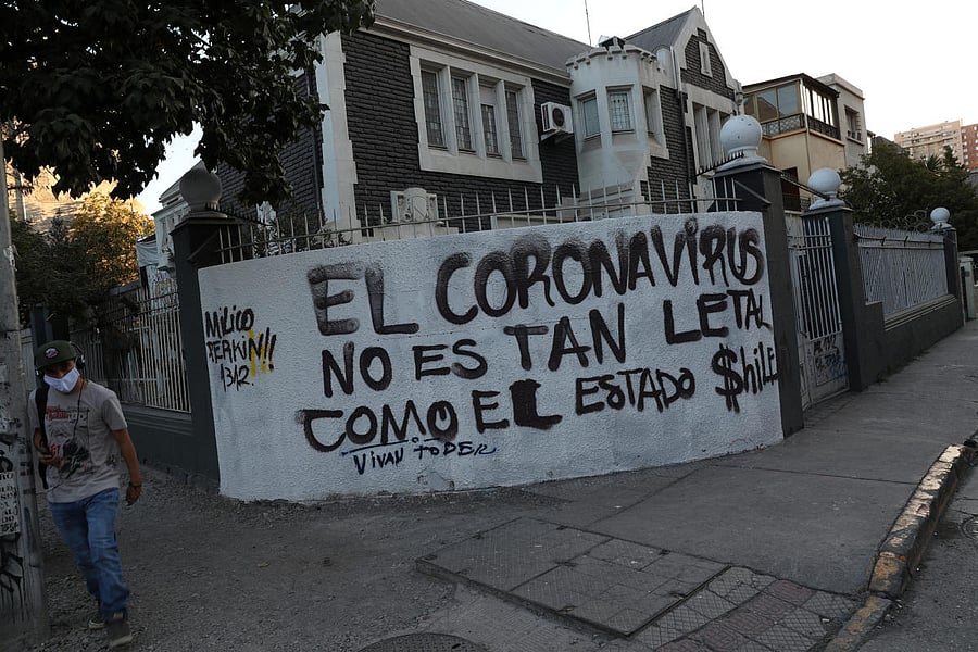 A man wearing a protective face mask walks past a graffiti reading "Coronavirus is not as lethal as the Chilean state" during the outbreak of coronavirus disease (COVID-19) in Santiago, Chile (Reuters Photo)