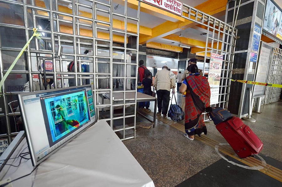 Passengers undergo baggage screening as they enter towards a platform of New Delhi Railway Station following resumption of passenger train services connecting major cities. PTI