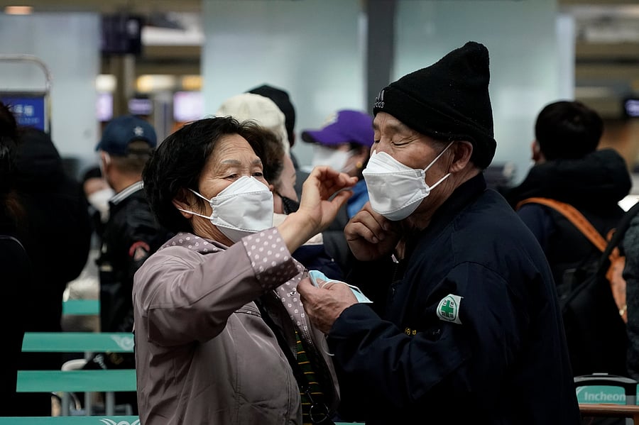 A woman wearing a mask to prevent contracting the coronavirus adjusts her husband's mask as they wait to check in at Incheon International Airport. (Credit: Reuters)