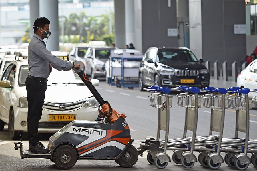 A member of airport staff wearing a facemask amid concerns over the spread of the COVID-19 novel coronavirus, pushes the trolleys at the Indira Gandhi International Airport in New Delhi. (Credit: AFP)