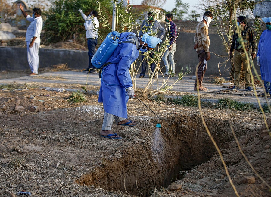 AMC worker disinfects a graveyard during a nationwide lockdown in the wake of deadly coronavirus, in Ahmedabad, Saturday, March 28, 2020. (PTI Photo)