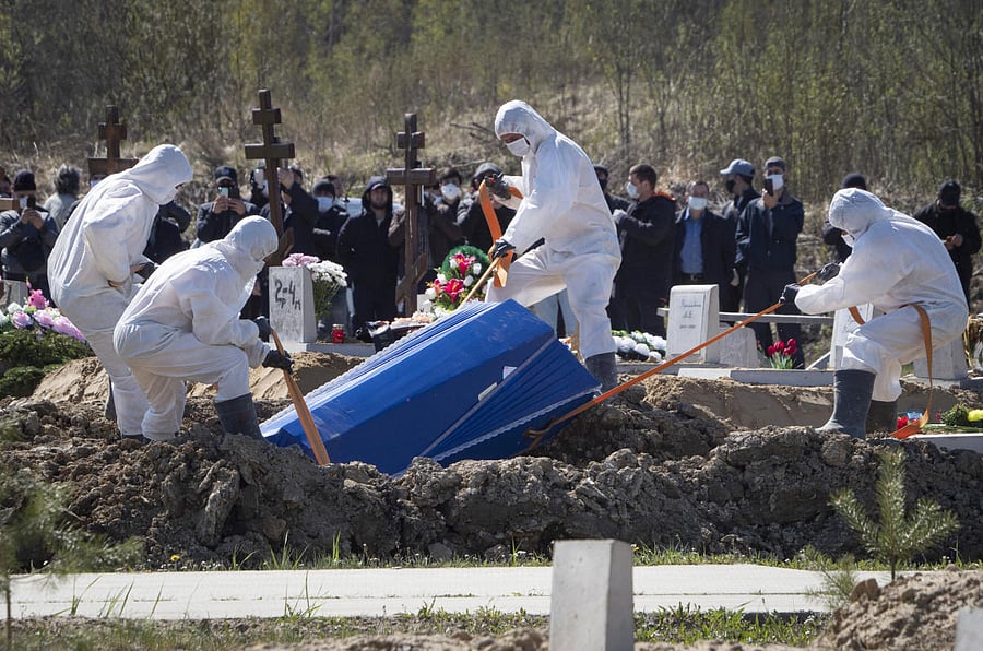 Grave diggers wearing protective suits bury a COVID-19 victim as relatives and friends stand at a safe distance, in the special purpose for coronavirus victims section of a cemetery in Kolpino, outside St.Petersburg, Russia. Credit: AP Photo